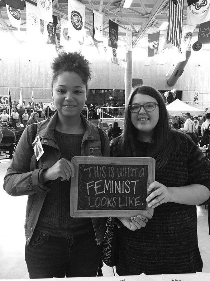 Juniors Gracie Hammond and Mykayla Sprague hold up a sign saying,”THIS IS WHAT A FEMINIST LOOKS LIKE,”  at a recent event hosted by GLSEN at Wichita State University.