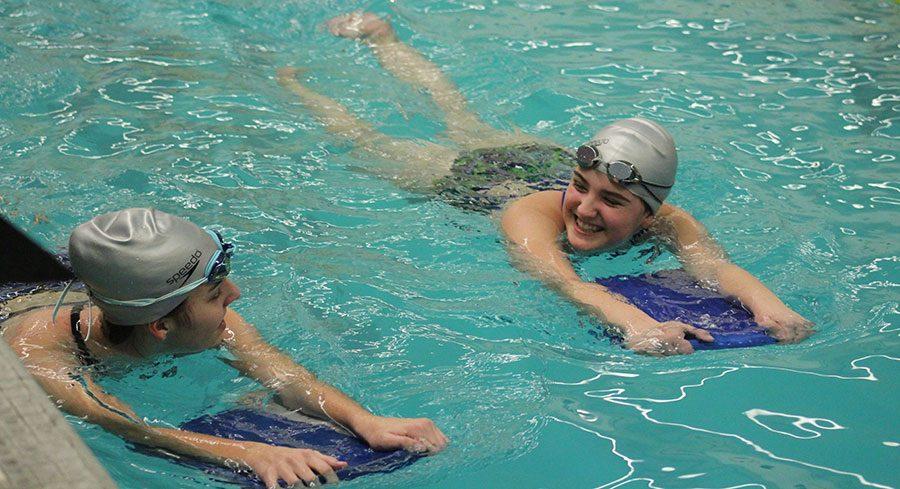 Preparing for the season, sophomores Hannah Becker and Kori Roberson warmup their muscles for practice. The girls swimming season began on February 27, 2017.