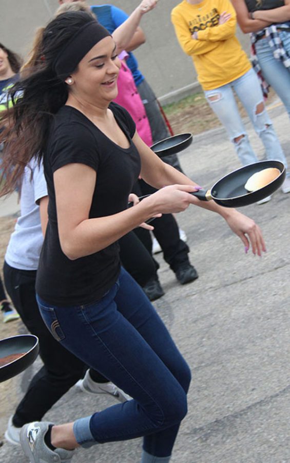 Senior Aylin Torres sprints while balancing her pancake in its skillet. Those who participated had to run around the back parking lot to declare the winner.