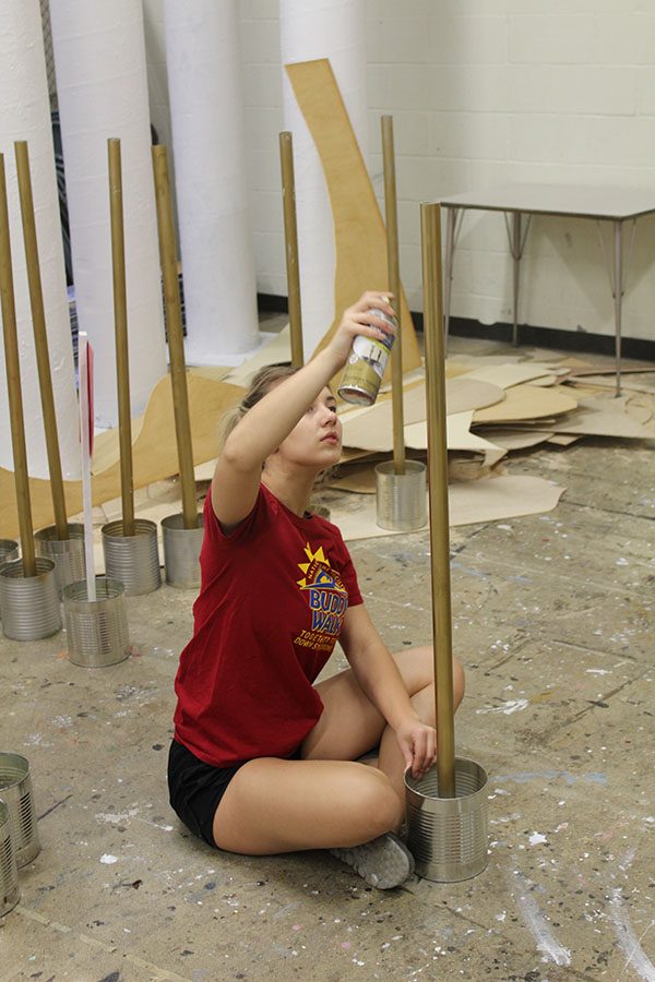With prom in mind, junior Kaylee Anderson paints the poles to be used to rope off the walk way at Promenade. Anderson, along with junior Garrett Mick painted a total of 32 poles.