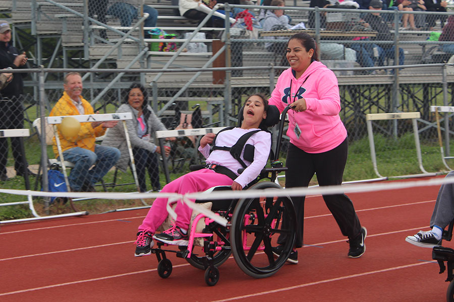 A Newton High staff member pushes her student across the finish line during the Adaptive P.E. track meet on Apr. 28.