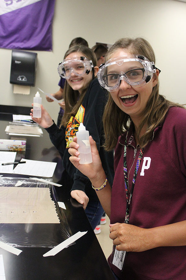 Excited to begin their lab, juniors Hannah Teater and Cattie Arrowsmith hold up their liquid acid solutions. The lab took two class periods to complete.