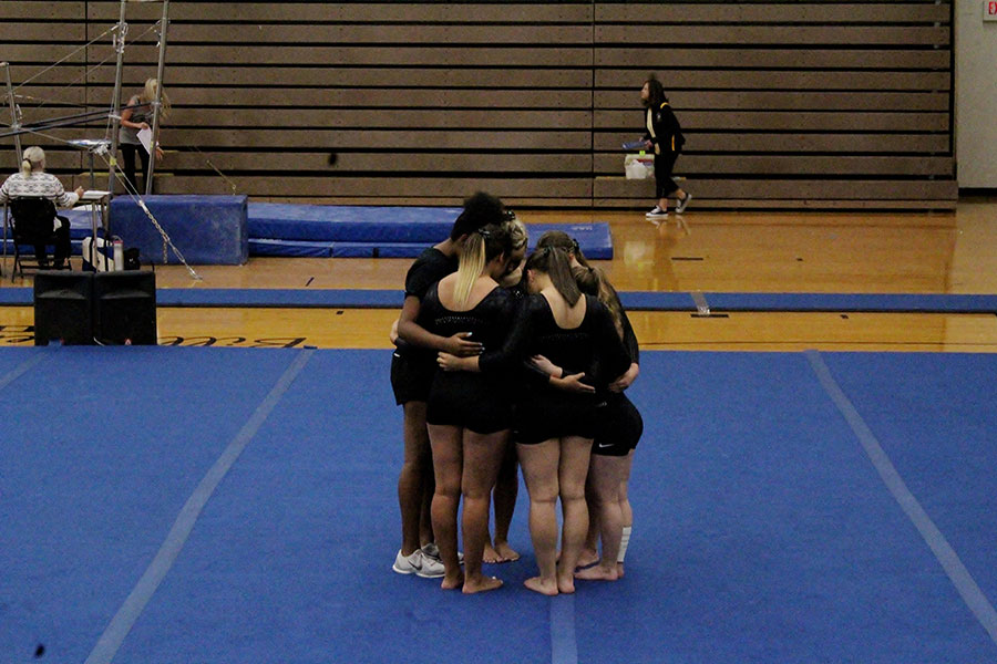 Before the start of the Sept. 8 home meet, the girls gymnastics team huddle together to prepare themselves. The meet started at 6:00 p.m. in Ravenscroft Gym.