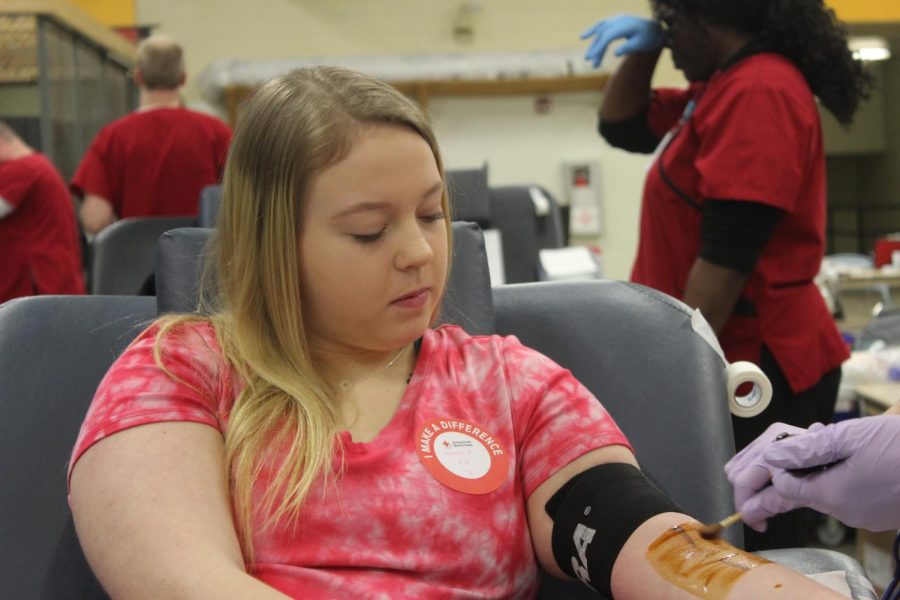 Watching with curiosity, senior Jasmine Powell gets her blood drawn during this years blood drive. This is Powells third year participating, having done it since her sophomore year. Its a good cause and I have good blood, Powell said. 