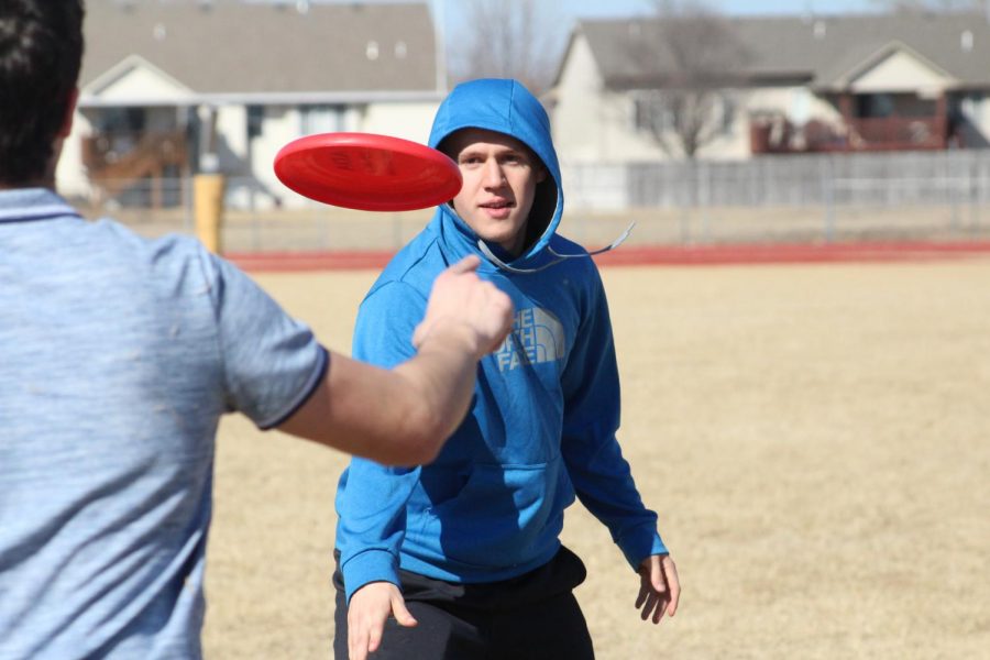 Junior Joel Thompson tosses the frisbee to a teammate on the football field on Mar 2. Most of Thompsons passes were successful.