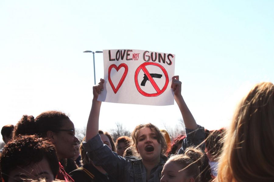 Senior Zoe Siemens holds up a “Love not guns” sign amongst the crowd. The walk out lasted a total of 17 minutes, in memory of the 17 lives lost in the Marjory Stoneman Douglas High School mass shooting in Parkland, Florida.