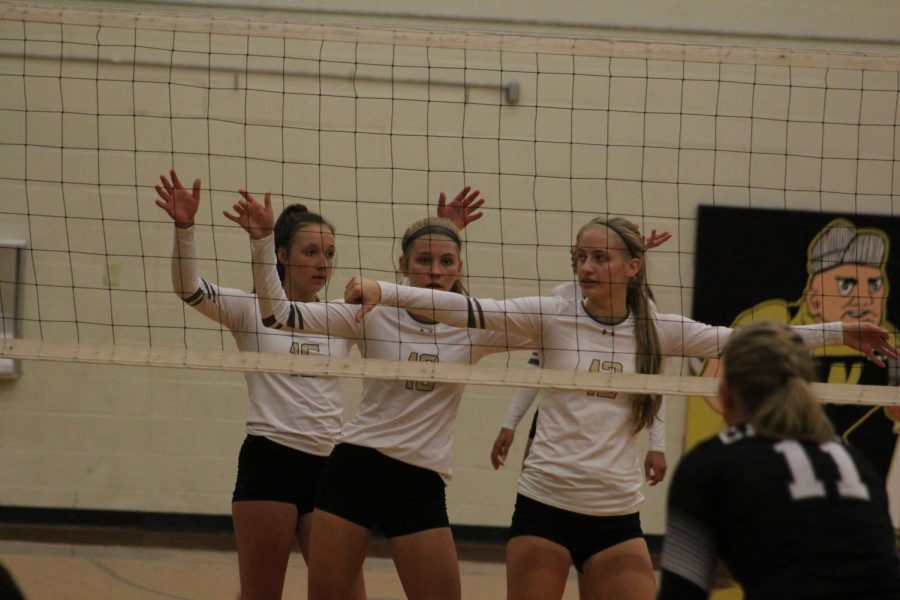 Senior Claire Slechta and sophomores Asha Regier and Lindsey Antonowich wait for opposing team to serve. The thumbs down means the setter is in the back row.