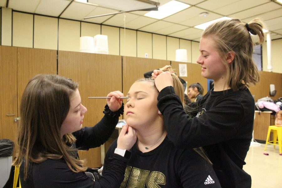 Working together, junior Becca Meyer and sophomore Madyson Groves help junior Reagan Moe get ready for their performance.