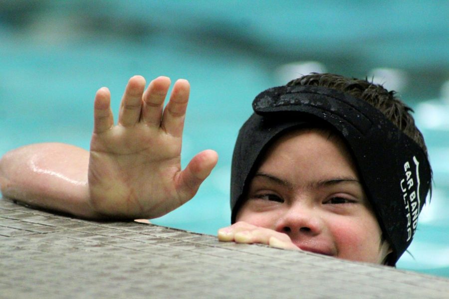 Student from middle school waves from the side of the pool. 
