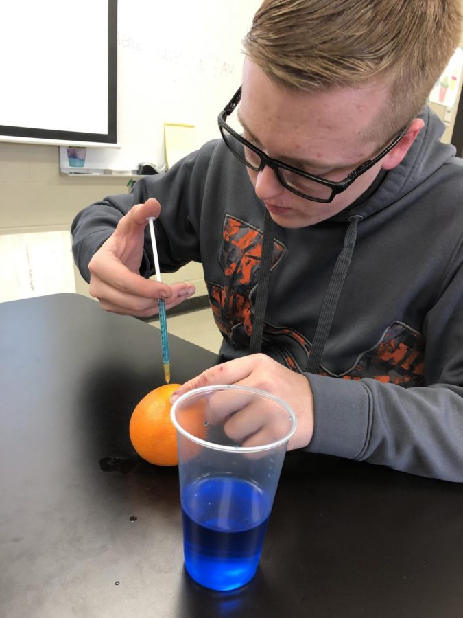 Sophomore Keaton Benedick uses the blue water to practice the intramuscular injection.