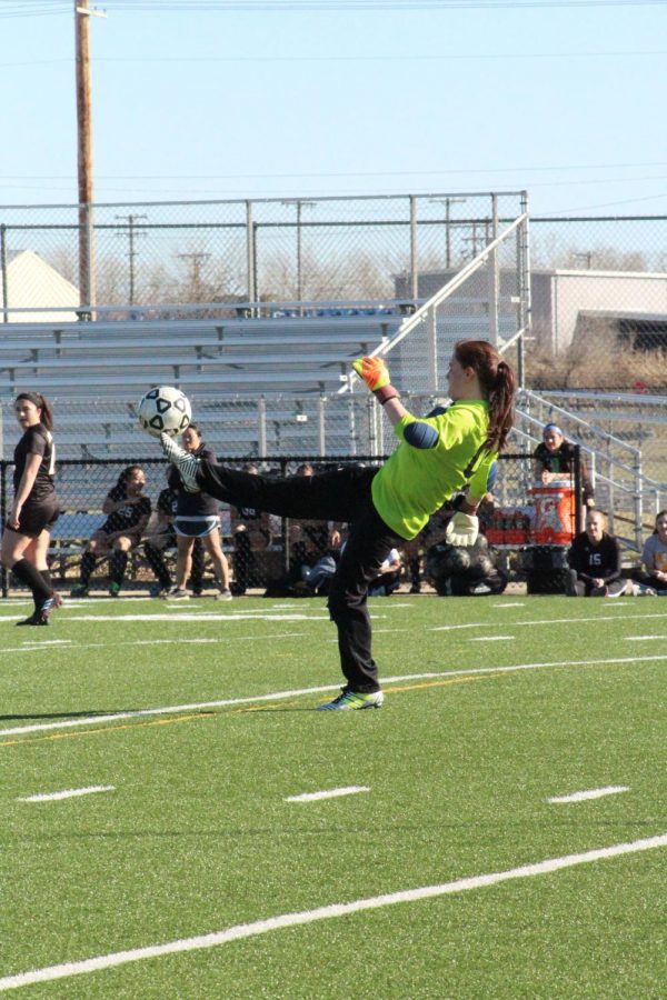 After guarding the ball, junior Cori Lyall kicks it across the field.