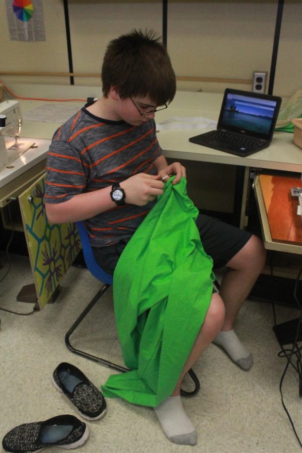 Sophomore Aaron Popp rips the seams on his green fabric. 