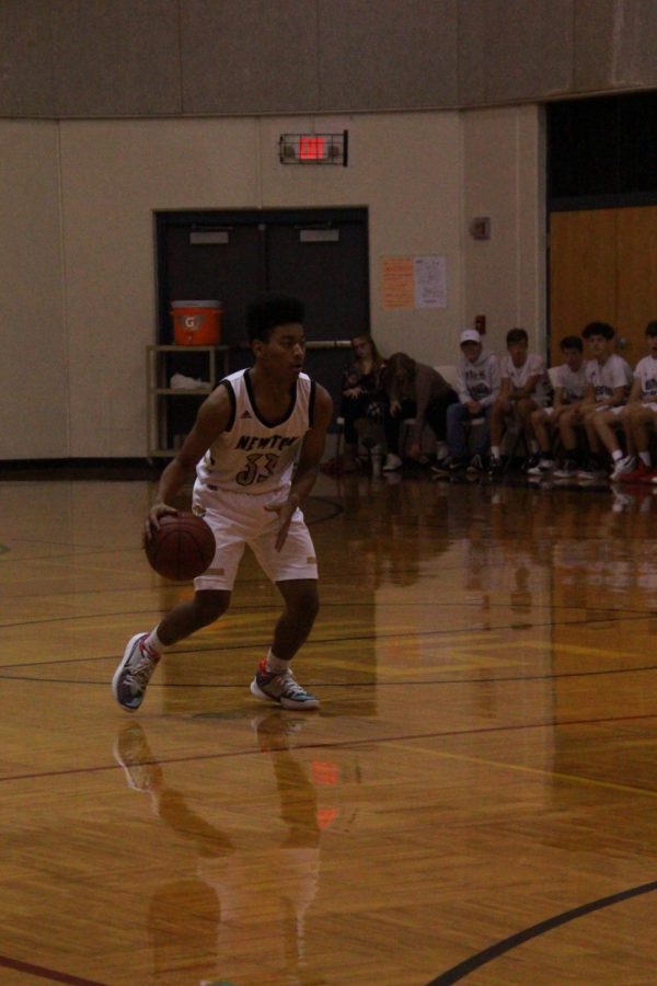 Looking around with ball,  junior Elijah Edwards dribbles to find his teammates.