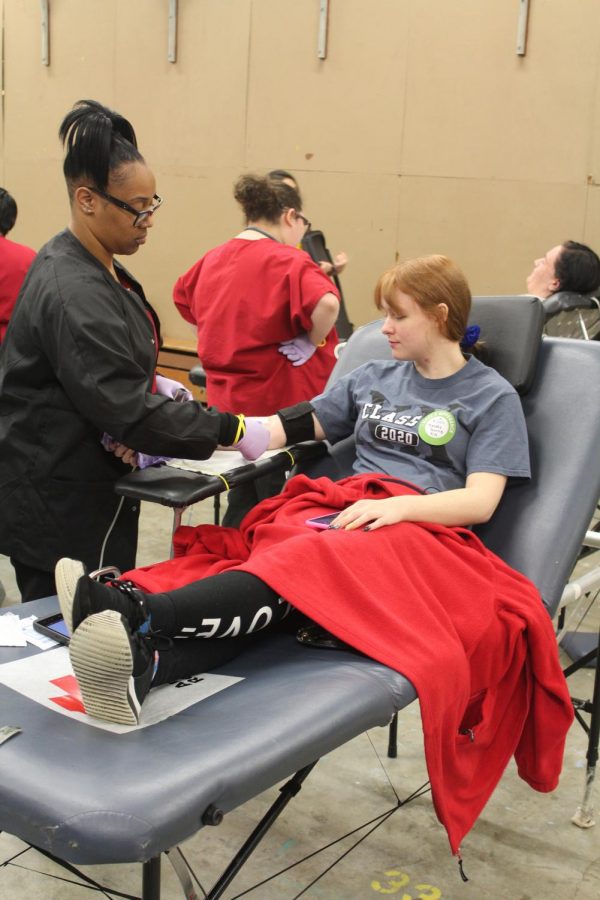 Senior Melody Burns has the red cross worker help get her ready to draw blood. 