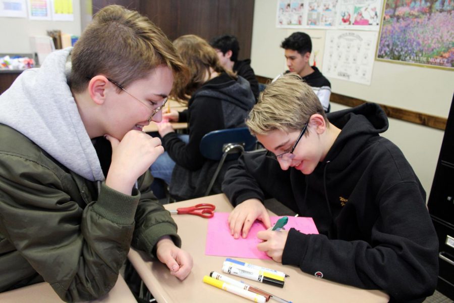 Working on their love coupons, freshmen Liam Hill and Jacob Antle write phrases in French. 