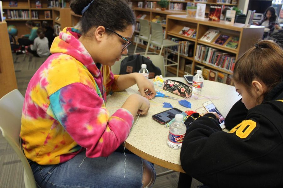Using tape to hold down her string, senior Ebony Tilden makes a friendship bracelet during first clubs on Nov. 8 of last year. Friendship Bracelet Making Club has only met three times this school year.