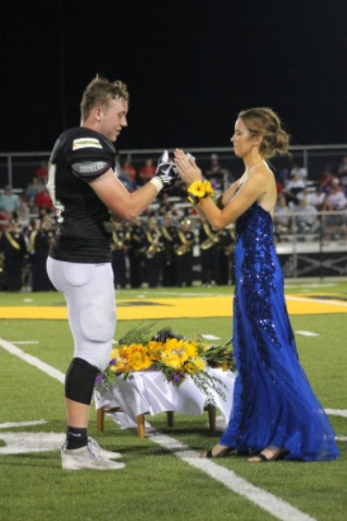 Alumni Drake Henrich and Maddie Edson preform their handshake in front of the crowd in the 2019 homecoming.