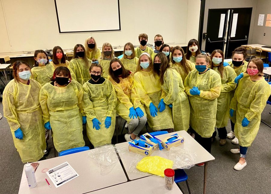 CNA students pose for a quick photo while dressed in personal protective equipment (PPE).
