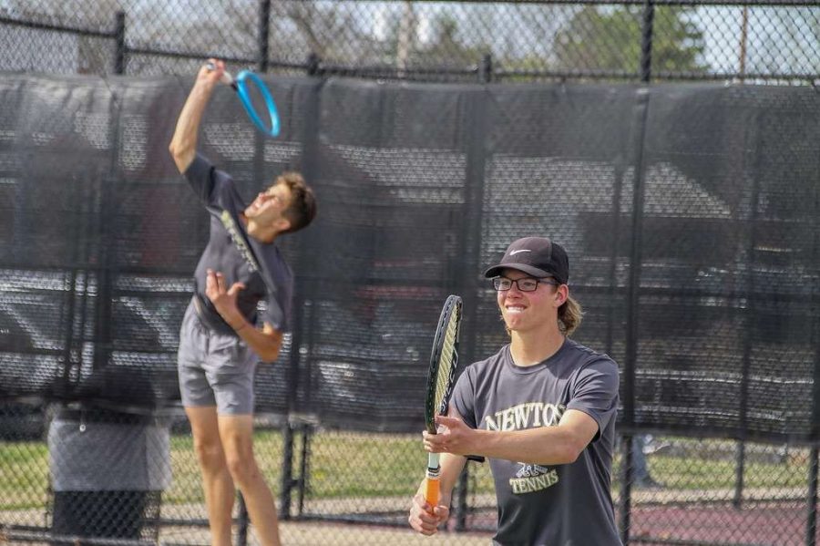 Senior+Jonah+Schloneger+jumps+in+order+to+hit+the+tennis+ball+while+sophomore+Justin+Franz+prepares+for+his+next+strike.