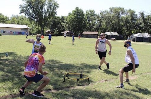 Senior Kaden Anderson and junior Simon Koontz play spike ball with their counselors during interest group time at camp Mennoscah.
