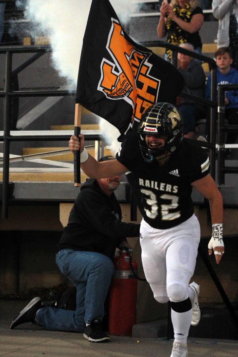 Leading the football team out of the locker senior Clayton Smith carries the Newton High School flag. 