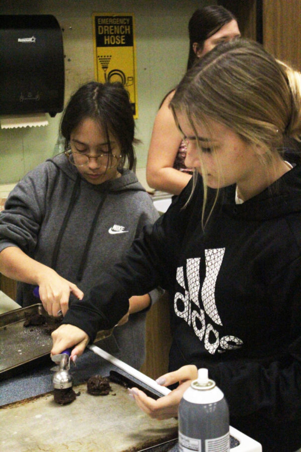 Senior Georgia Garcia and junior Megan Rice work together to start putting the cookie dough on the cookie sheets.