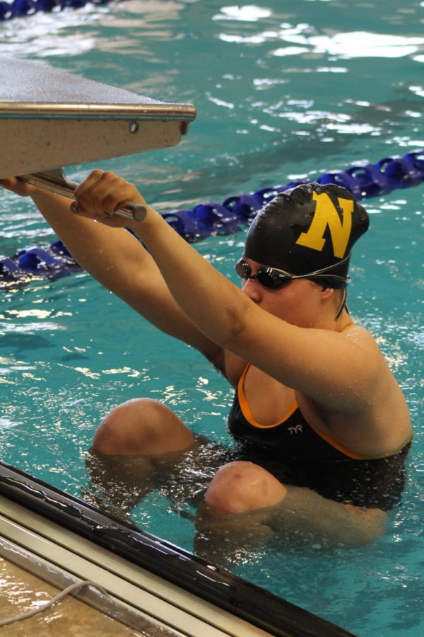 Before racing in the 100 yard backstroke event, freshman Anne Koontz places her feet in preparation to launch backwards into the water. 