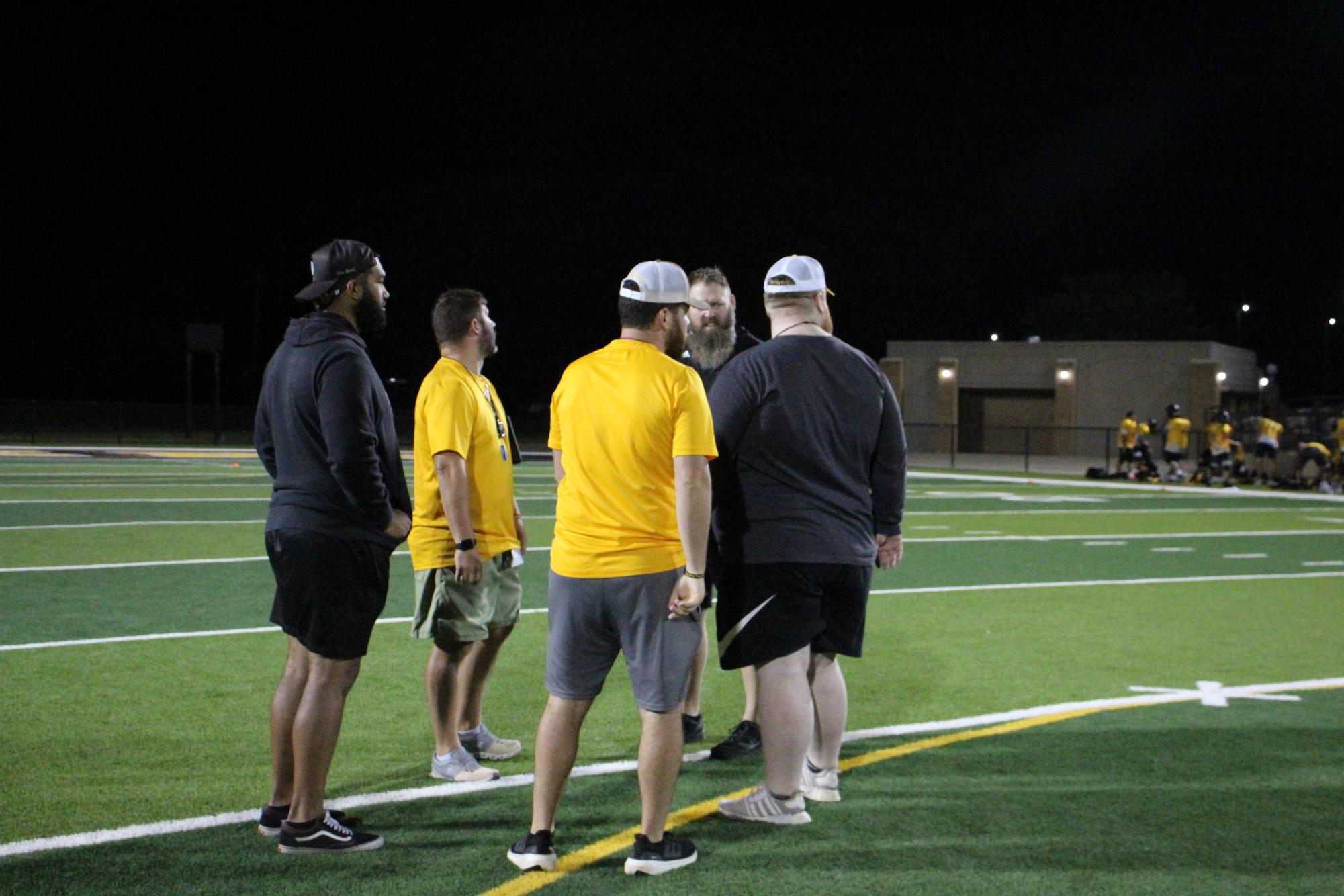 Football staff talk during morning practice.