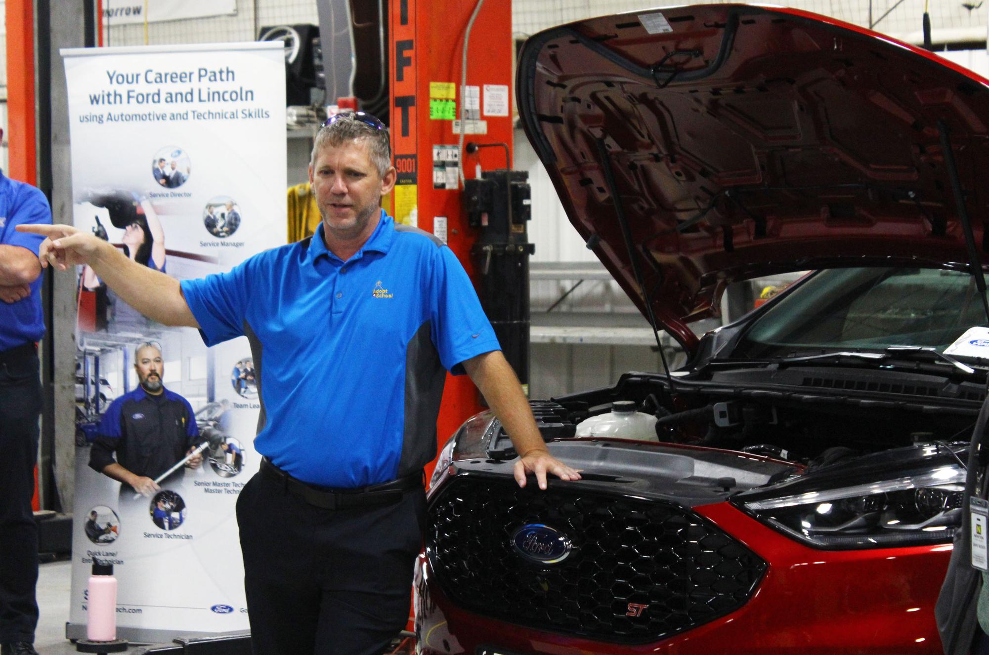 Kyle Eck, CEO Rusty Eck Ford, talks to students and staff about the importance of automotive service technicians at a celebration of the donation of a Ford Edge to the CTE auto shop program at Newton High School. 
