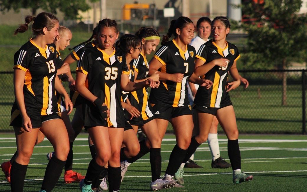 Girls' soccer team celebrates a goal.
